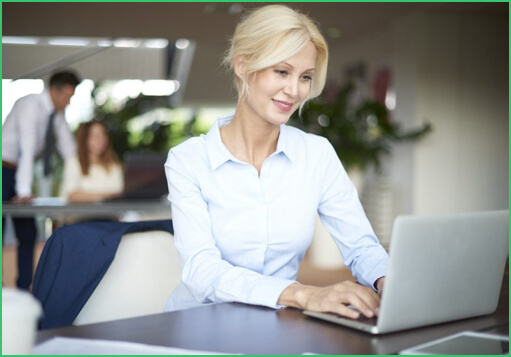 Women are smiling while working on laptops.